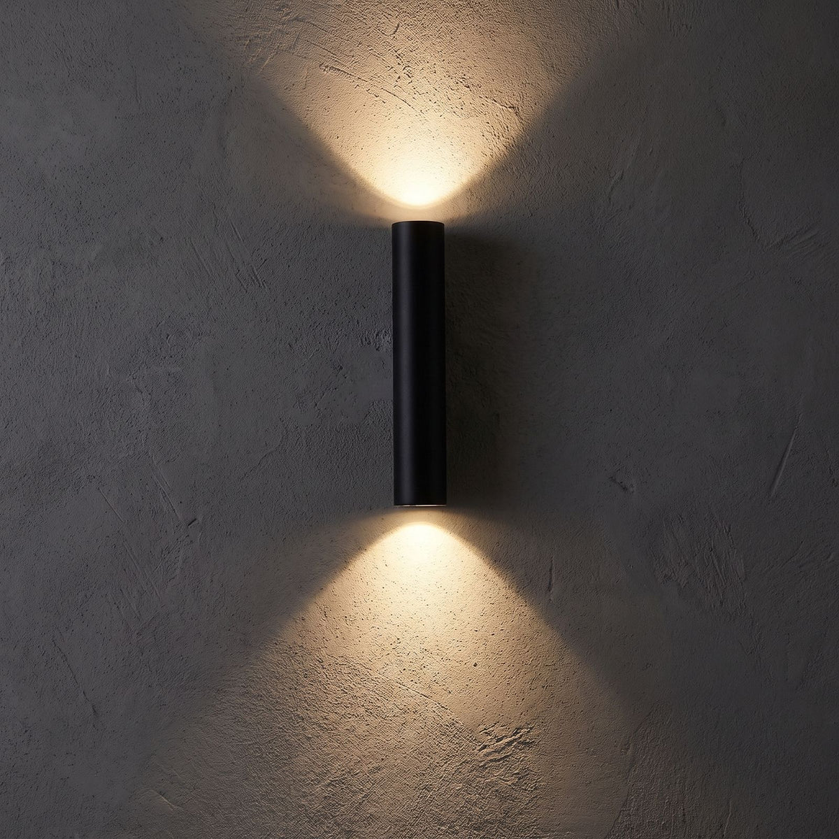 Narrow Aluminium Bar Up Down Wall Light glowing on a plaster wall at night