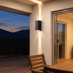 Black up down outdoor wall light on an alfresco patio wall at dusk