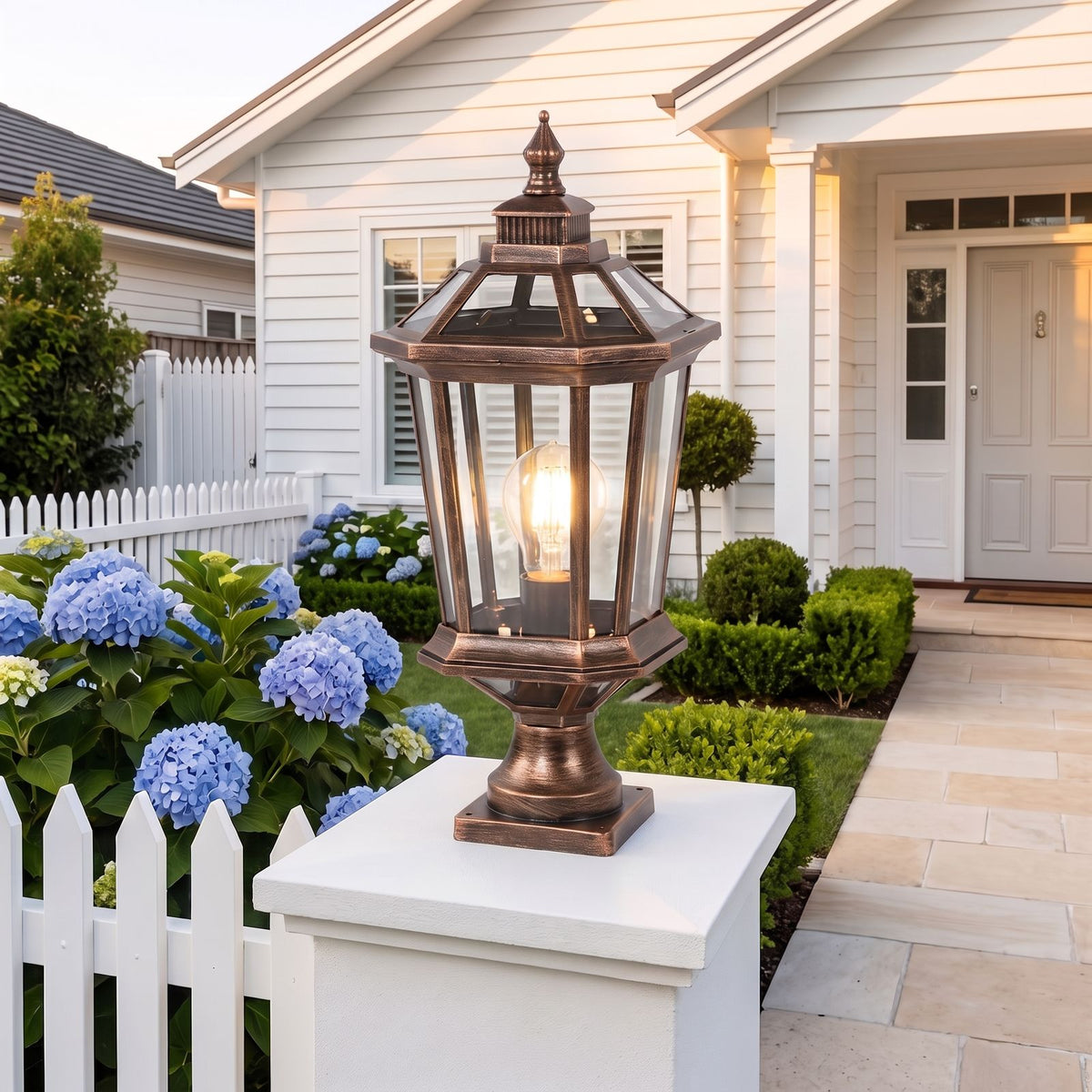 Octagonal Clear Glass Lantern Pillar Light in bronze on a front entry pillar at dusk