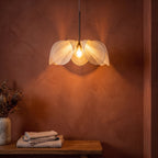 Open Petal Fabric Flower Pendant Light glowing against a plaster wall at night