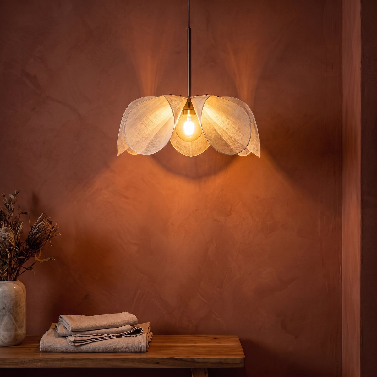 Open Petal Fabric Flower Pendant Light glowing against a plaster wall at night