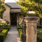 Open Square Frame Stainless Steel Deck Post Light on a gate pillar at the front entrance at golden hour