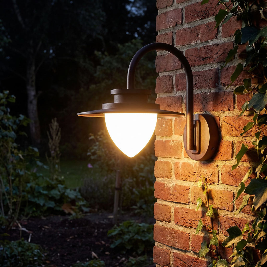 Pine Cone Glass Gooseneck Outdoor Wall Light glowing on a garden wall at night