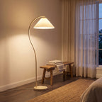 Pleated shade arc floor lamp in a bedroom corner beside a dresser
