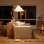 Pleated shade arc floor lamp behind a sofa at night