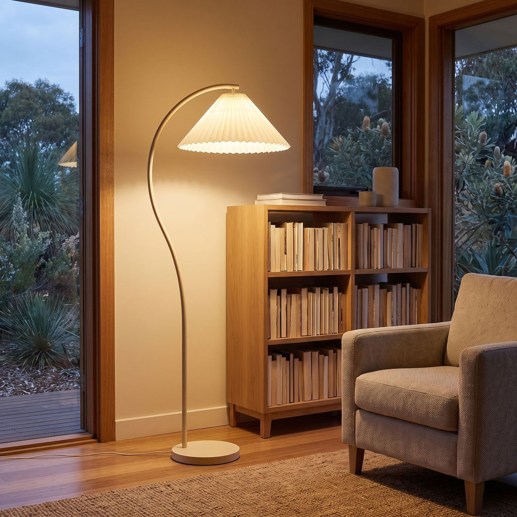 Pleated shade arc floor lamp in a reading corner beside a bookshelf