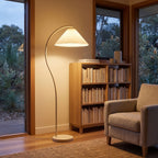 Pleated shade arc floor lamp in a reading corner beside a bookshelf