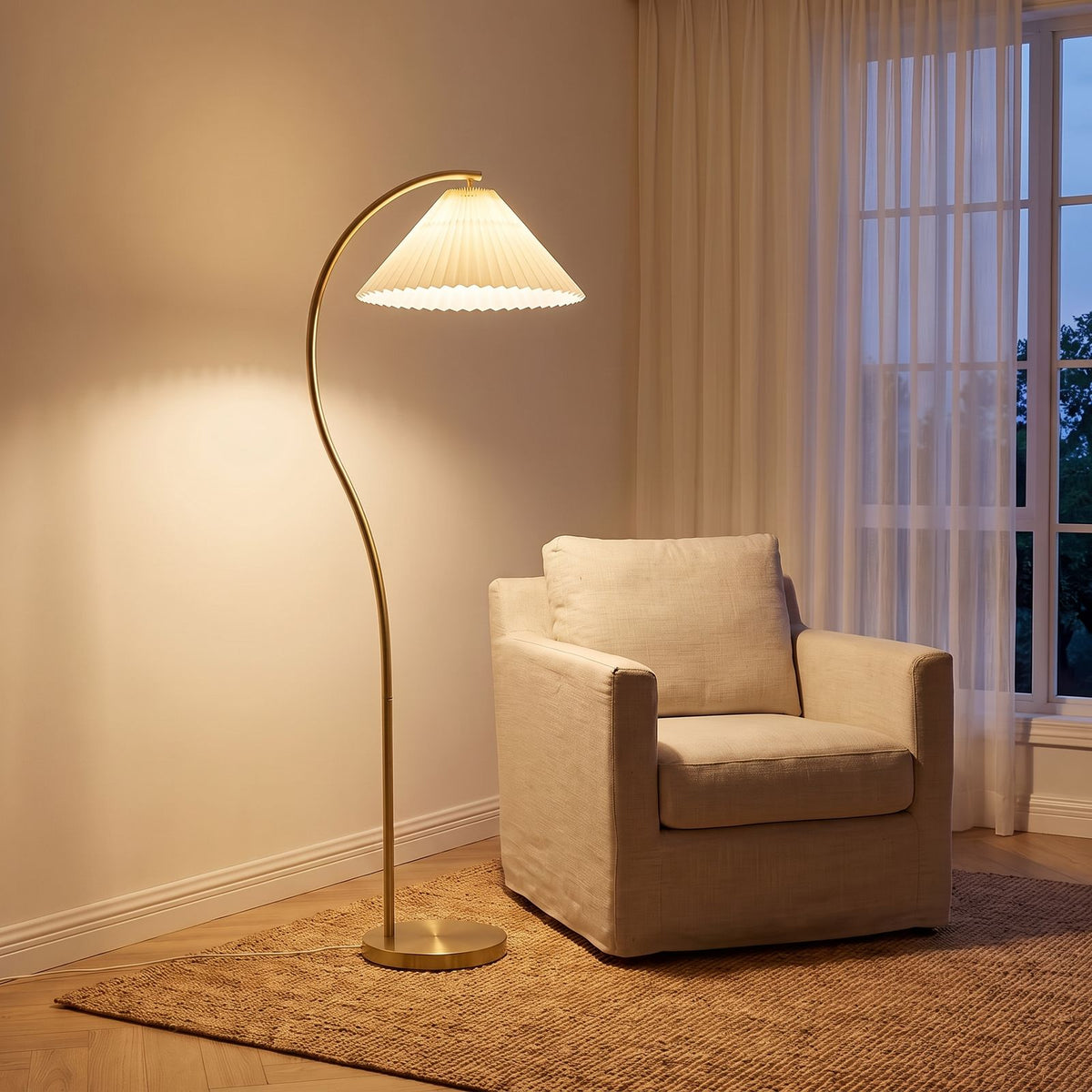 Pleated Fabric Shade Arc Floor Lamp with a gold stem beside an armchair in a living room corner
