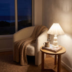 Scalloped Pleated Shade Bobbin Table Lamp in white on a side table beside an armchair in a living room reading corner