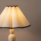 Scalloped Pleated Shade Bobbin Table Lamp close view of the scalloped pleated shade with black trim, switched on