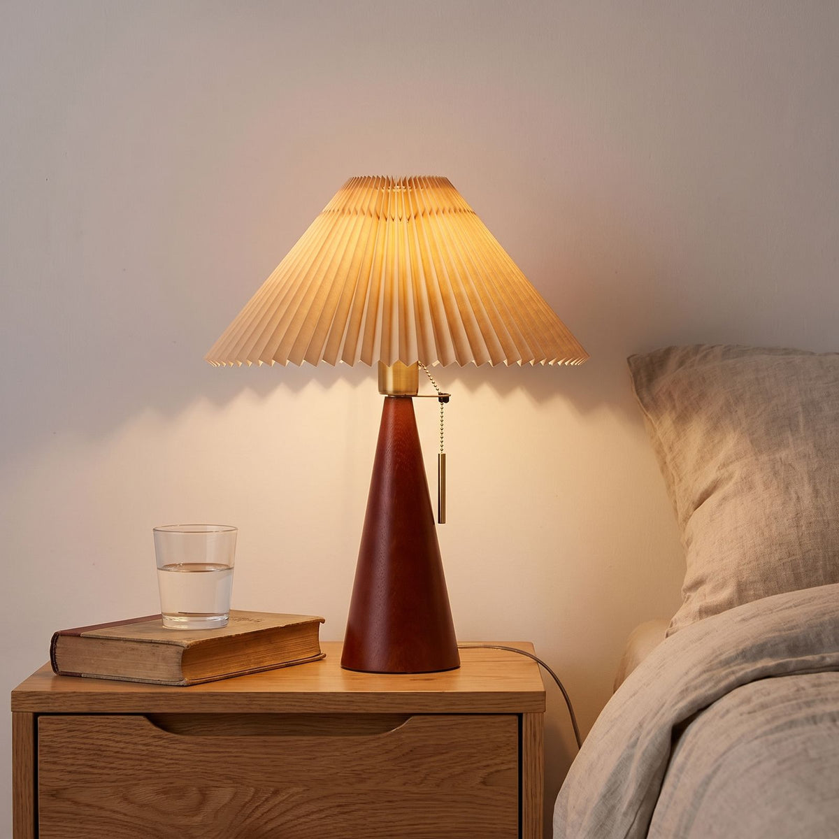 Pleated Shade Cone Wood Base Pull Chain Table Lamp on a bedside table