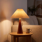 Pleated shade table lamp with walnut cone base on a side table beside a sofa