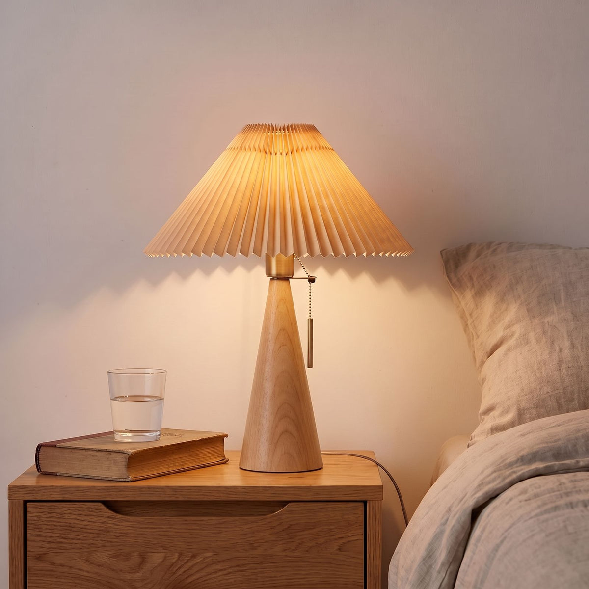 Pleated Shade Cone Wood Base Pull Chain Table Lamp with a natural wood base on a bedside table