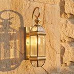 Polished Brass Clear Glass Outdoor Wall Light, close view at 45 degrees on a stone wall
