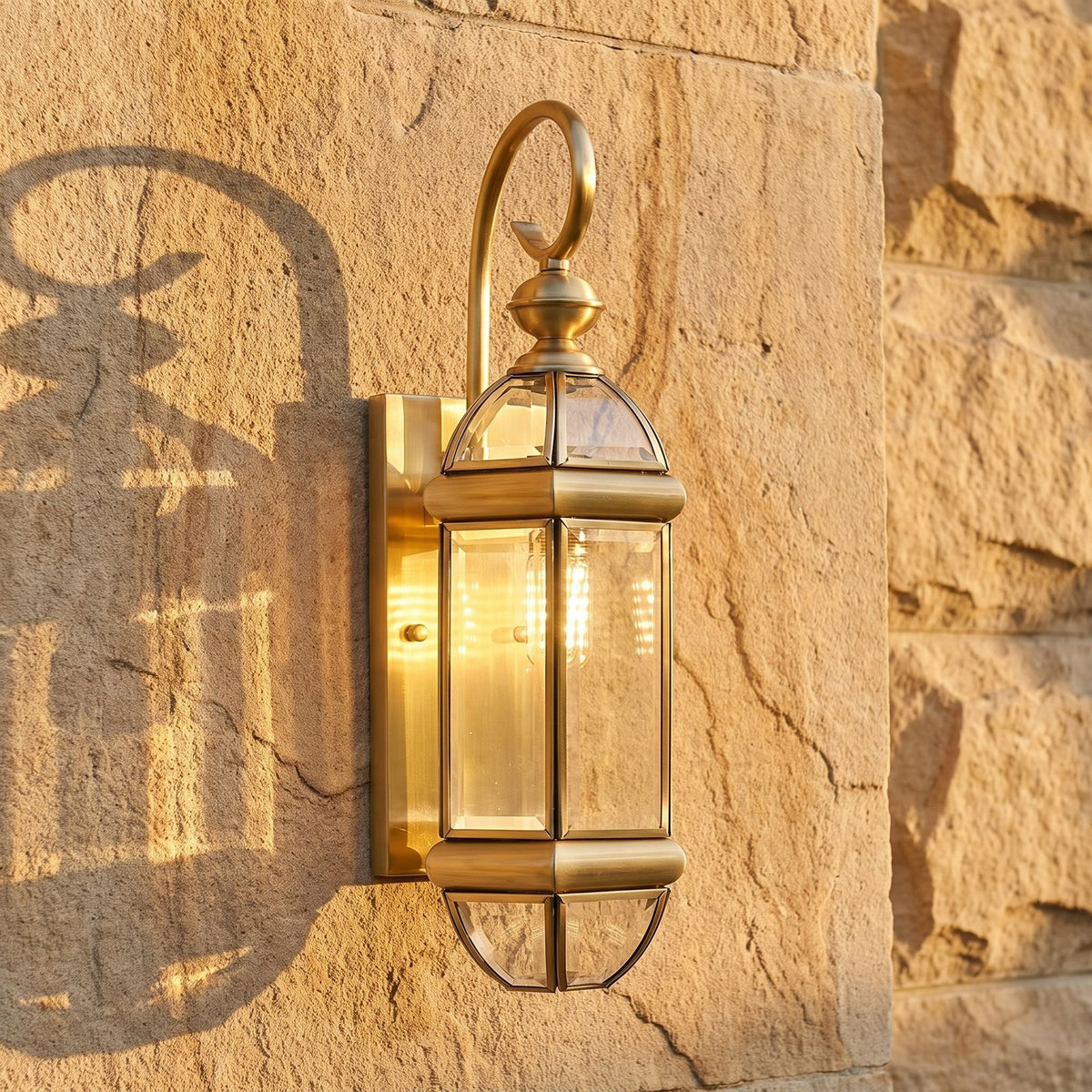 Polished Brass Clear Glass Outdoor Wall Light, close view at 45 degrees on a stone wall