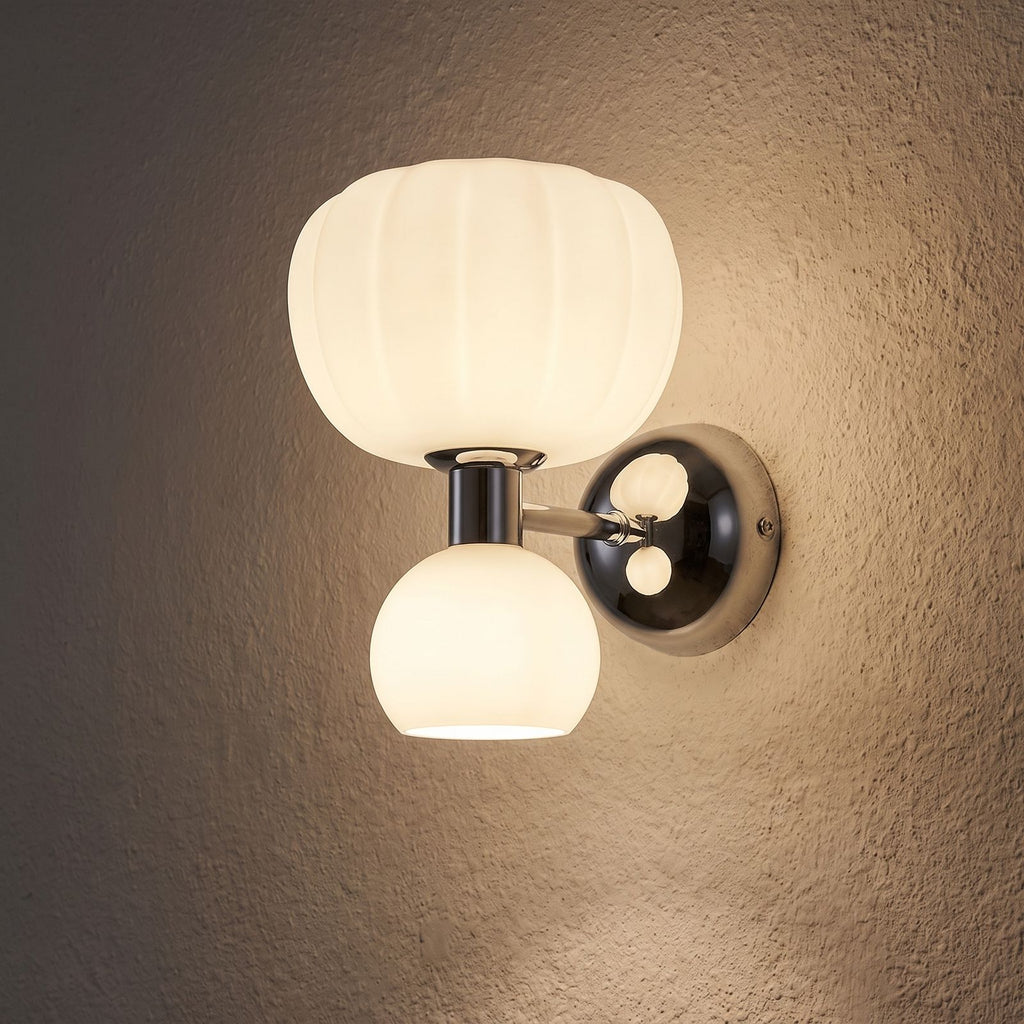Pumpkin Shade Chrome Wall Sconce glowing on a plaster wall at night