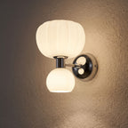 Pumpkin Shade Chrome Wall Sconce glowing on a plaster wall at night
