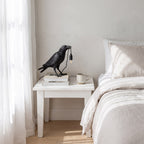 Raven Sculpture Resin Table Lamp on a bedside table in a coastal bedroom