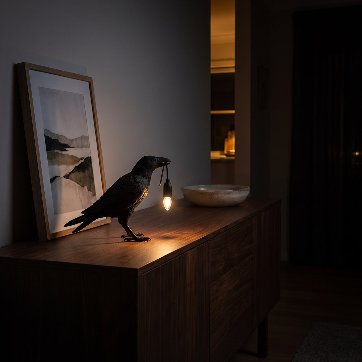 Raven Sculpture Resin Table Lamp glowing on a walnut sideboard at night