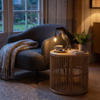Raven Sculpture Resin Table Lamp on a rattan side table beside an armchair at dusk