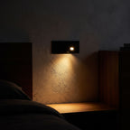 Recessed Pop-Out Bedside Reading Wall Light glowing on a plaster wall at night