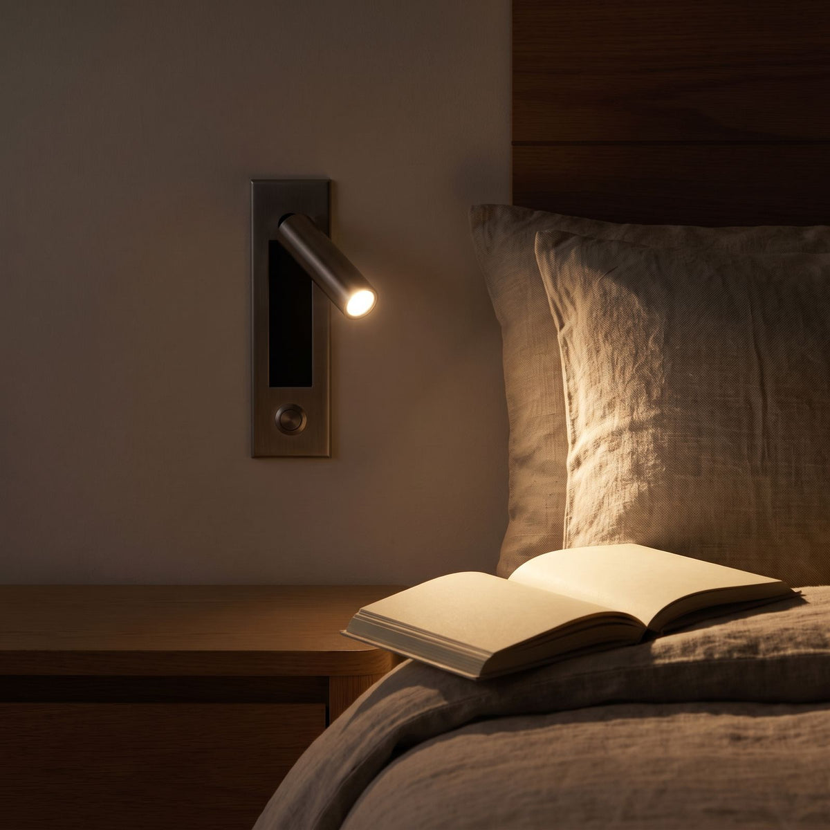 Recessed swivel tube reading wall light over a book at night