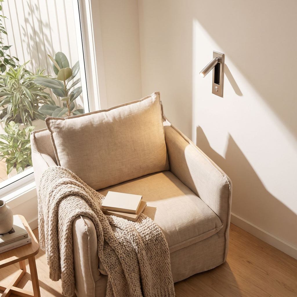 Recessed swivel tube reading wall light beside a reading armchair in daylight