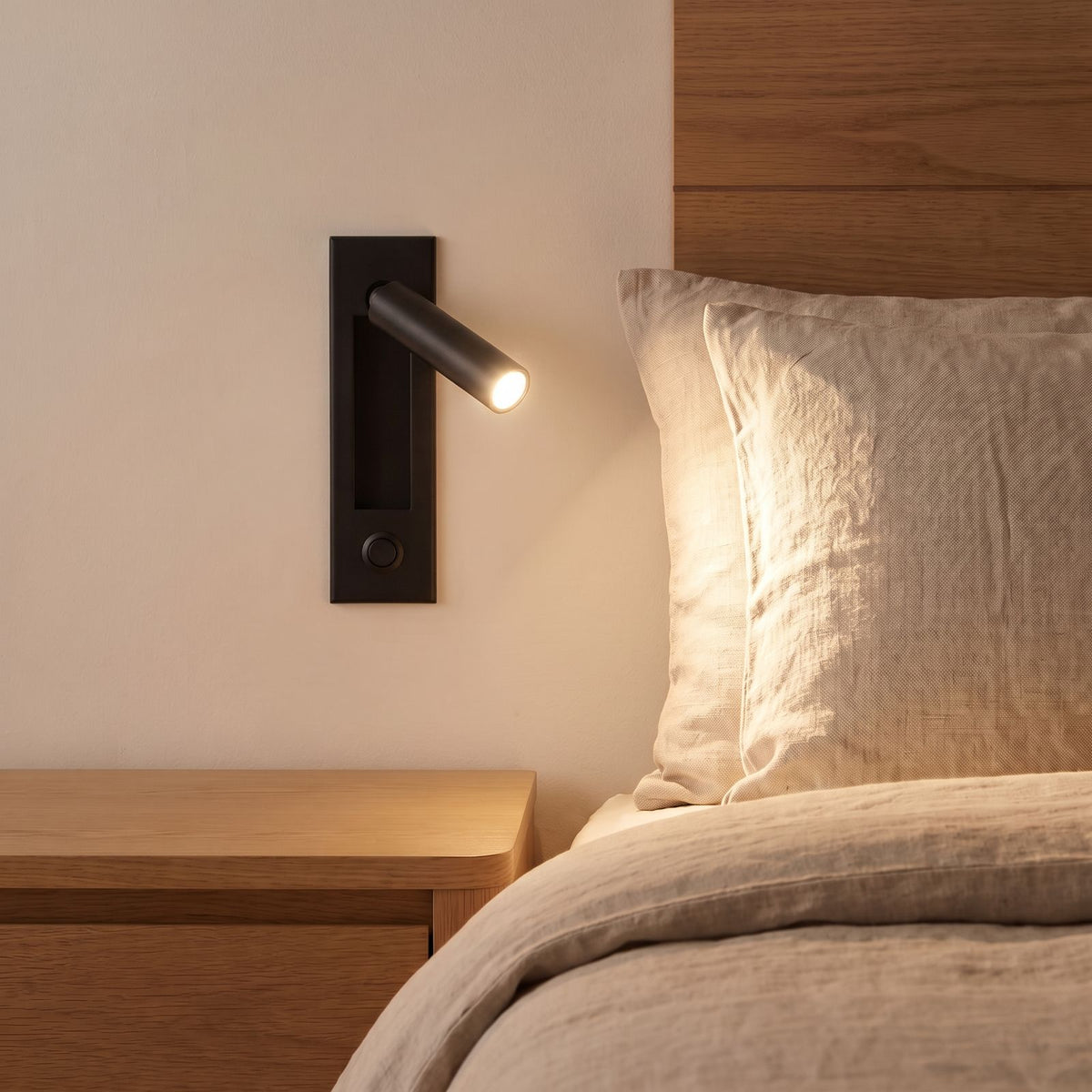 Recessed Swivel Tube Bedside Reading Wall Light in matte black beside a bed