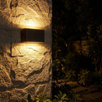 Rectangular Acrylic Up Down Outdoor Wall Light glowing on a garden wall at night