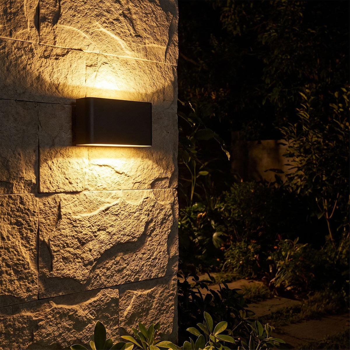Rectangular Acrylic Up Down Outdoor Wall Light glowing on a garden wall at night