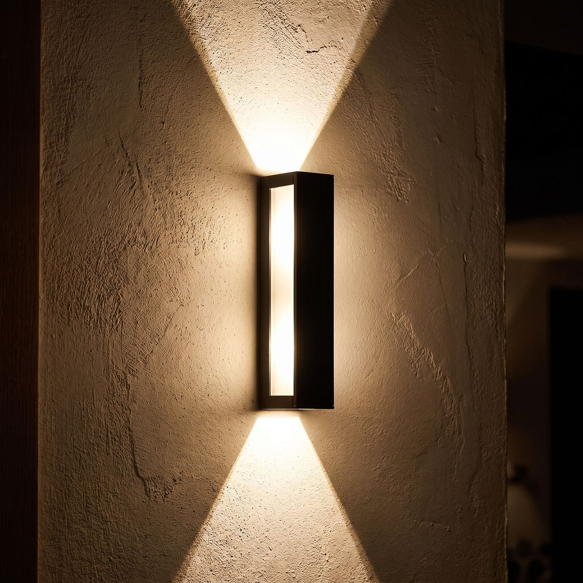 Rectangular Aluminium and Glass Up-Down Wall Light glowing on a plaster wall at night