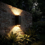 Rectangular Metal Up Down Outdoor Wall Light glowing on a garden wall at night