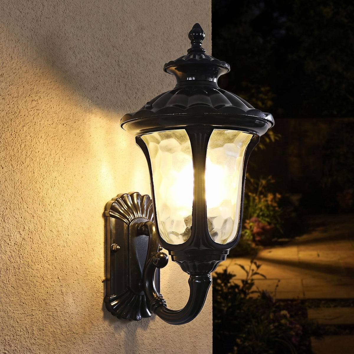 Retro Black Frosted Glass Outdoor Wall Light glowing on a garden wall at night