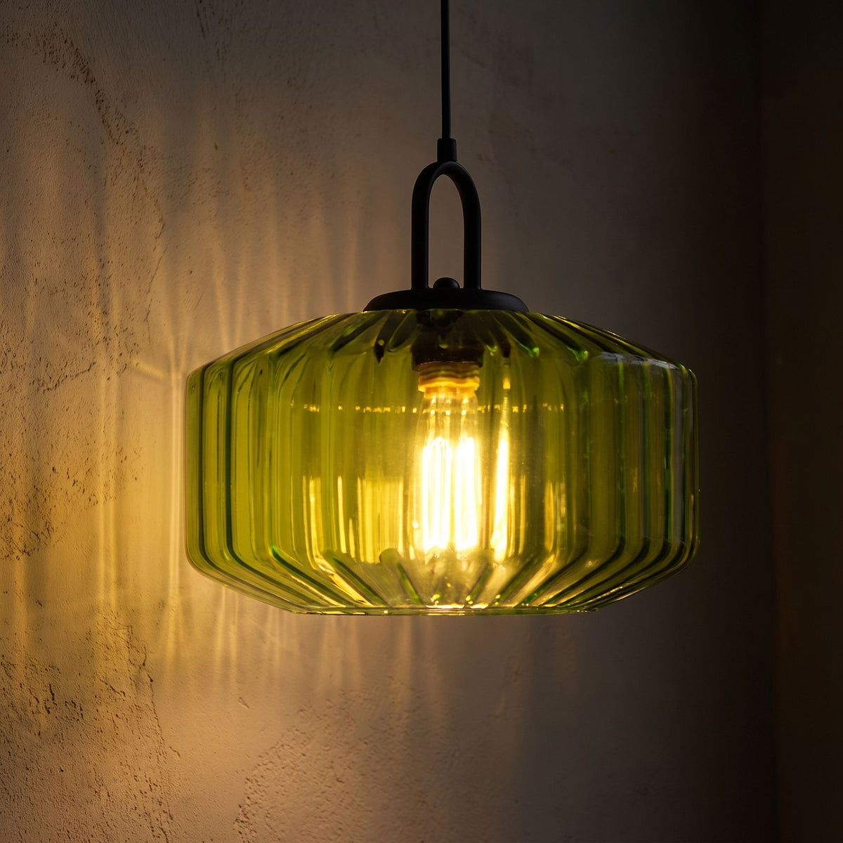 Ribbed Coloured Glass Pendant Light glowing against a plaster wall at night