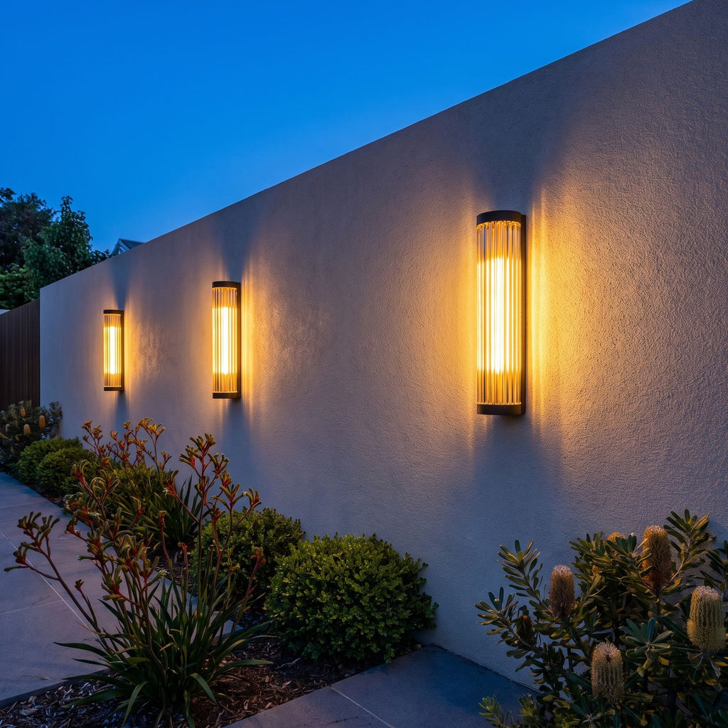 Three Ribbed Glass Cylinder Outdoor Wall Lights along a rendered garden wall at dusk
