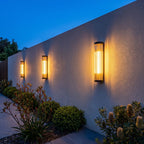 Three Ribbed Glass Cylinder Outdoor Wall Lights along a rendered garden wall at dusk