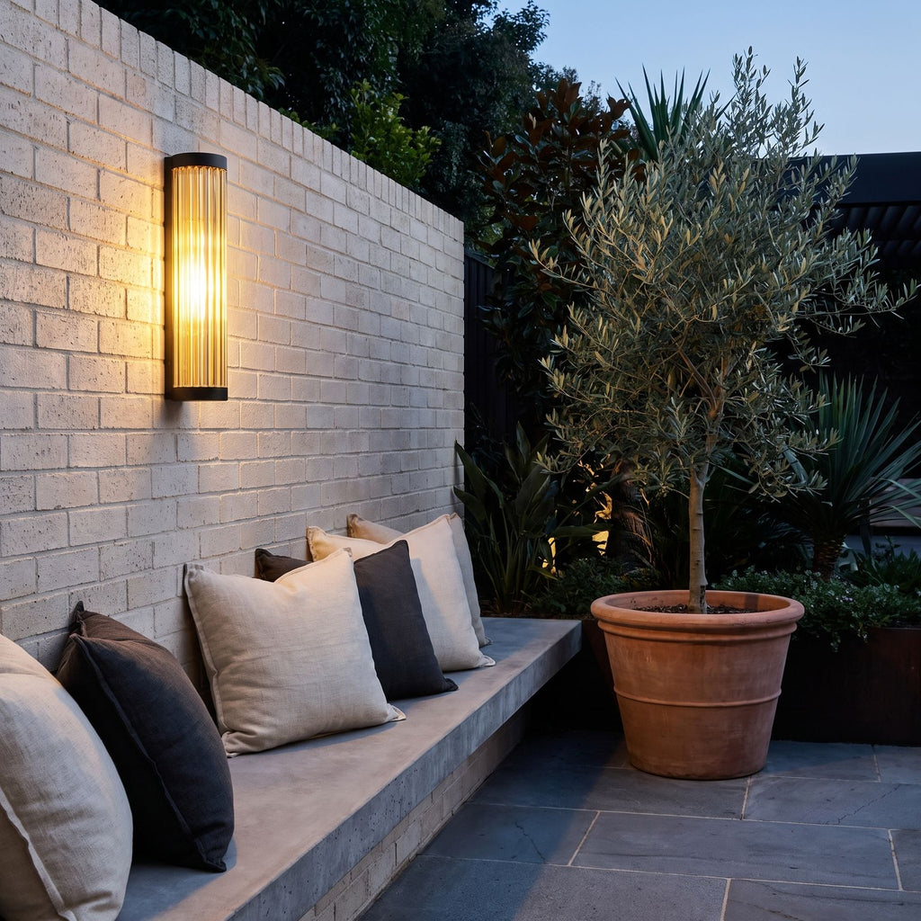 Ribbed Glass Cylinder Outdoor Wall Light above a concrete bench on a brick courtyard wall