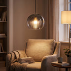 Ribbed Glass Globe Pendant Light above a reading armchair
