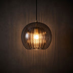Ribbed Glass Globe Pendant Light glowing against a plaster wall at night