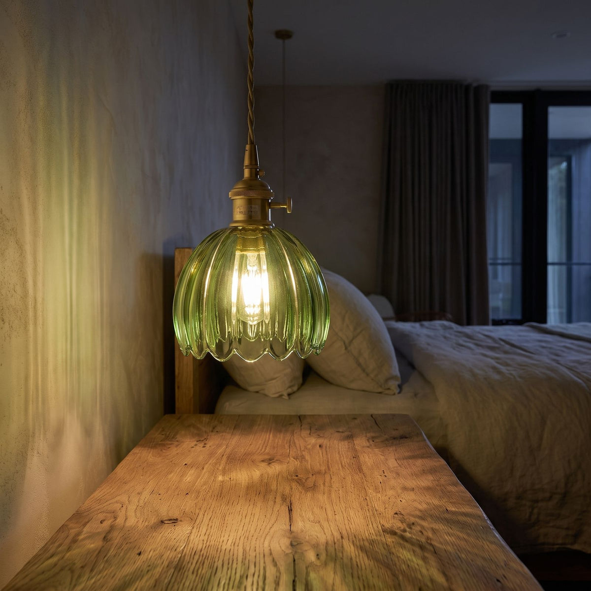 Ribbed tulip glass mini pendant light over a bedside table at night