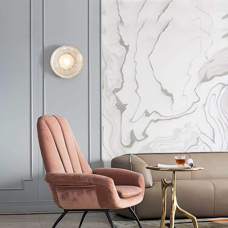 Round glass wall light beside an armchair in a living room