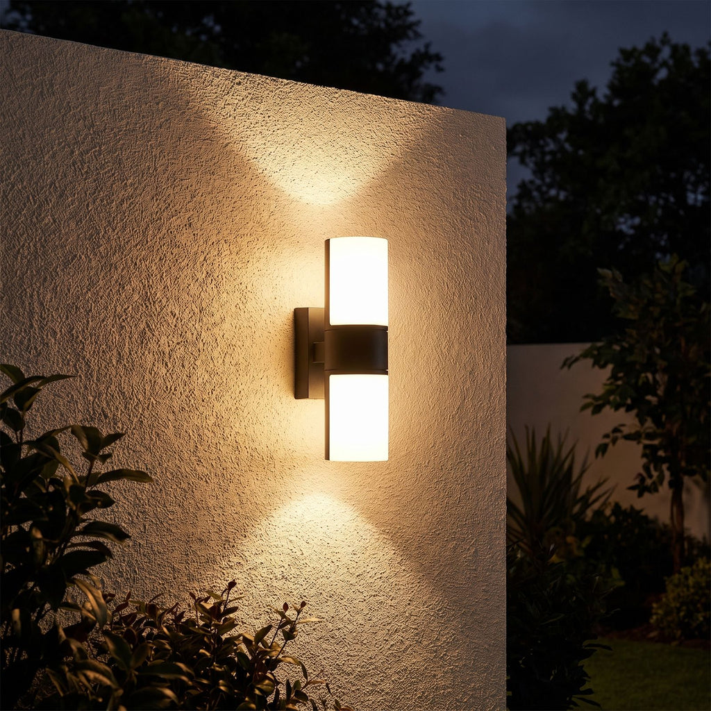 Rotatable Metal Band Acrylic Cylinder LED Outdoor Wall Light glowing on a garden wall at night