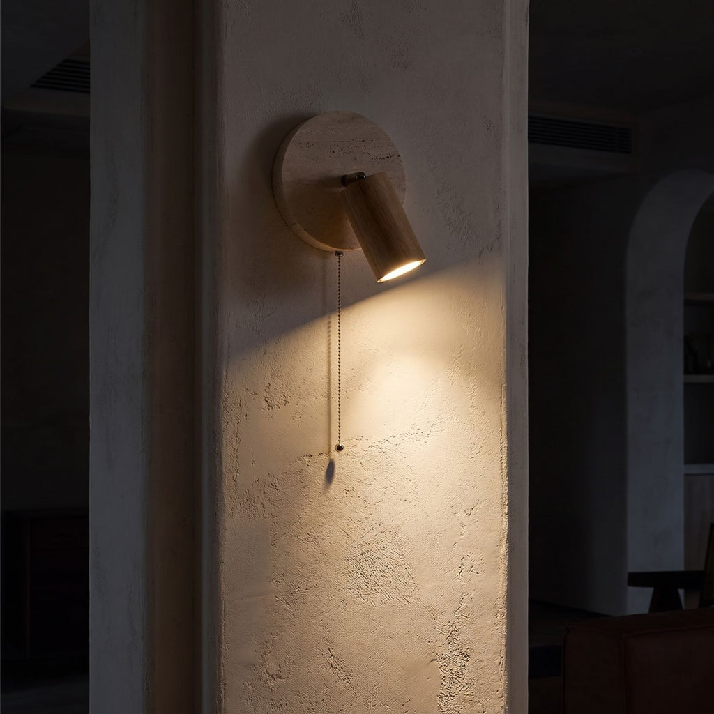Rotatable Travertine Spotlight Wall Light glowing on a plaster wall at night