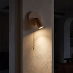 Rotatable Travertine Spotlight Wall Light glowing on a plaster wall at night