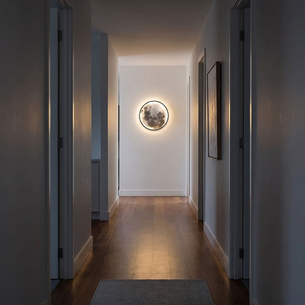 Round 3D Moon Black Frame LED Wall Light in warm white at the end of a hallway at night