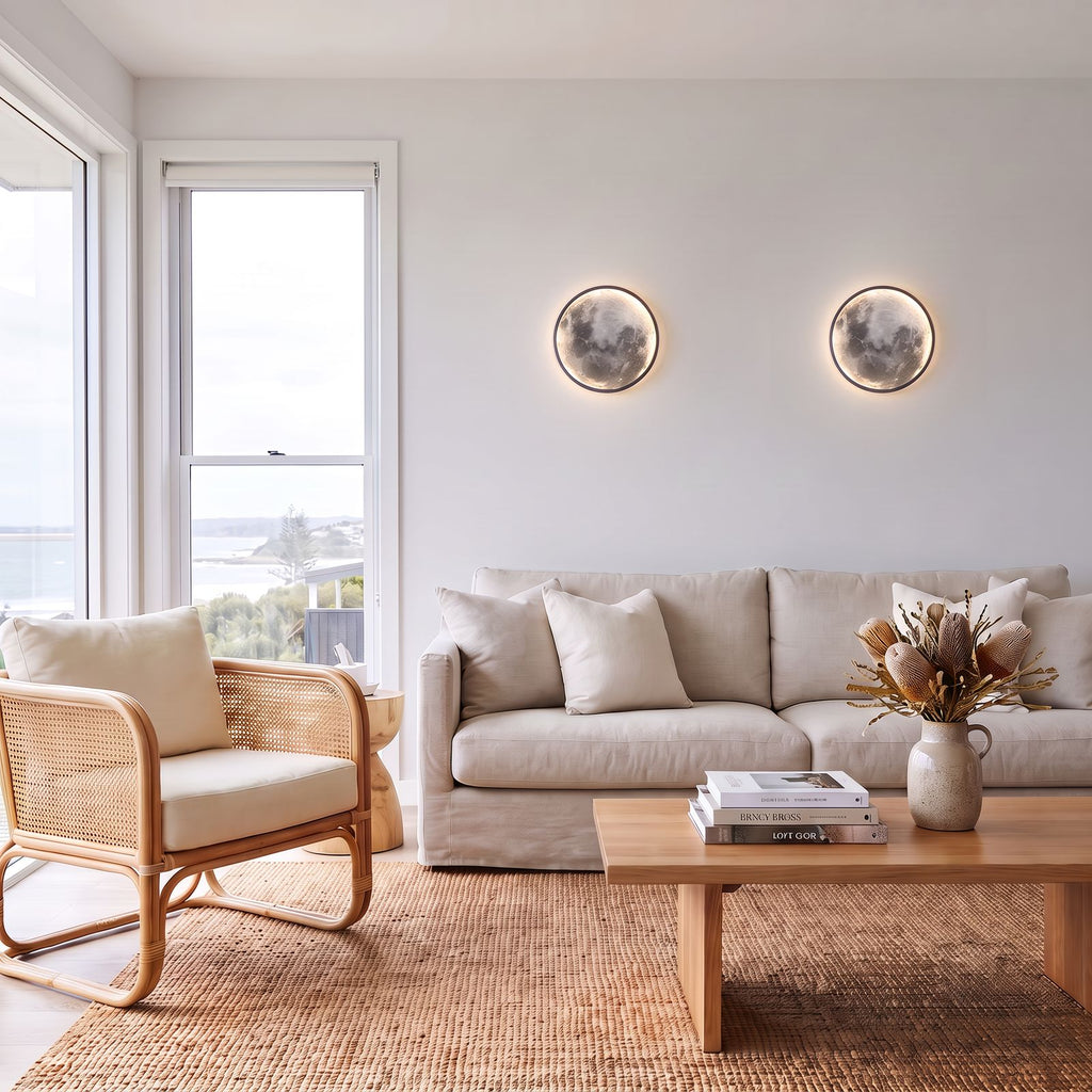 Round 3D Moon Black Frame LED Wall Light pair above a linen sofa in a coastal living room in daylight