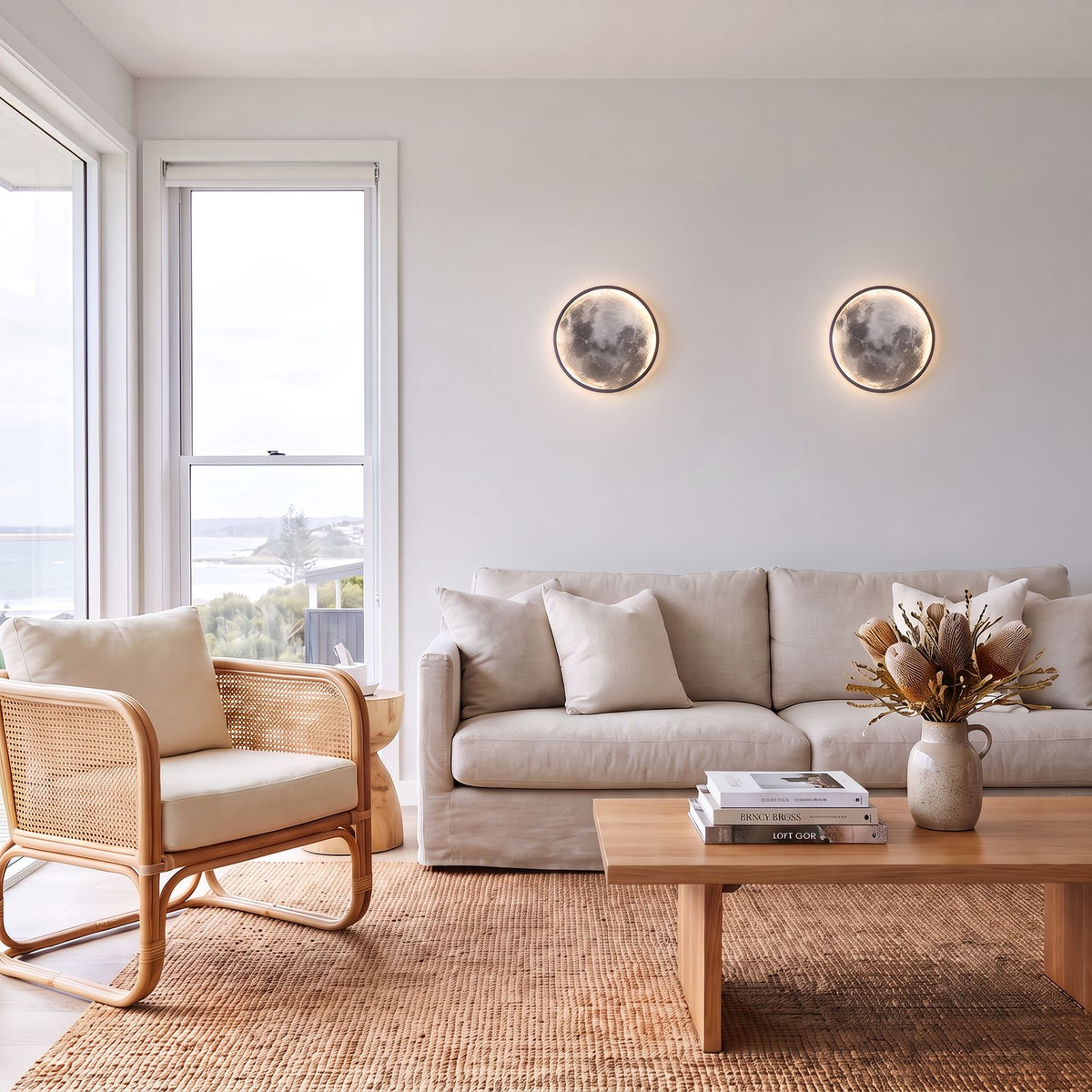 Round 3D Moon Black Frame LED Wall Light pair above a linen sofa in a coastal living room in daylight