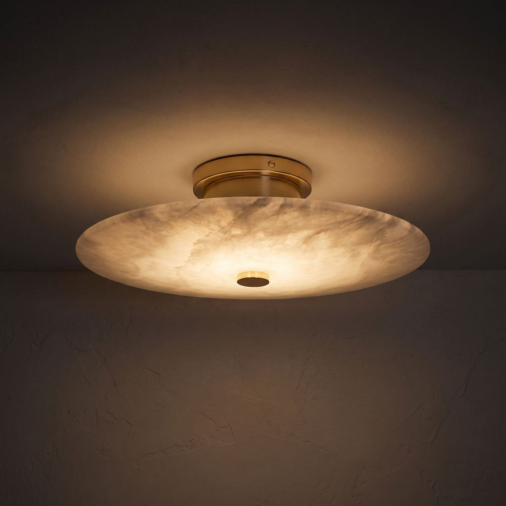 Round Alabaster Flush Wall and Ceiling Light glowing on a plaster wall at night
