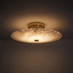 Round Alabaster Flush Wall and Ceiling Light glowing on a plaster wall at night