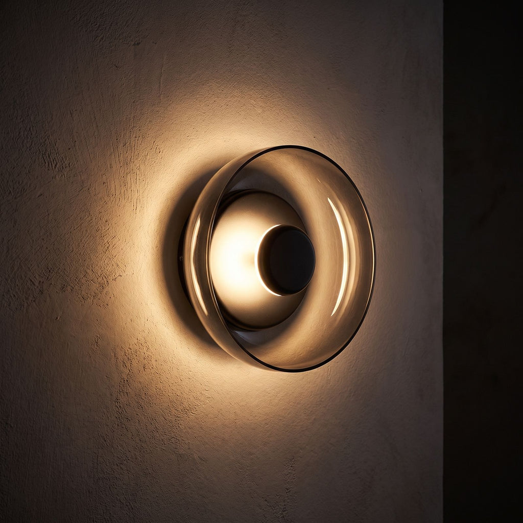 Round Glass Dish LED Wall Light glowing on a plaster wall at night